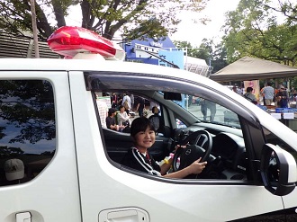 アクティブ交番の運転席に座り、笑顔の小学生
